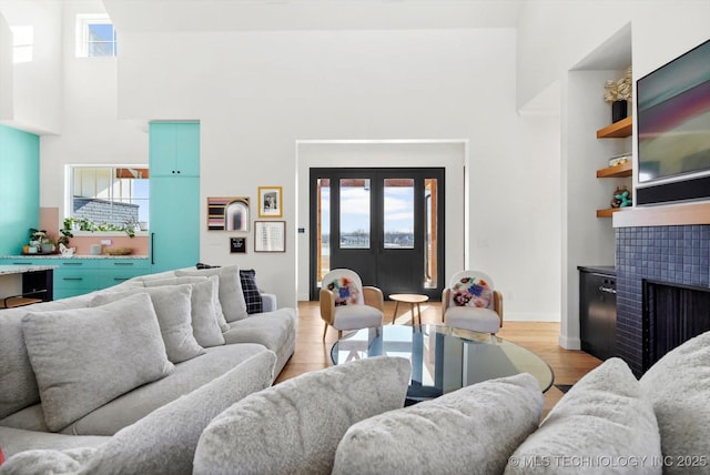 living room with a healthy amount of sunlight, light hardwood / wood-style floors, and a tile fireplace