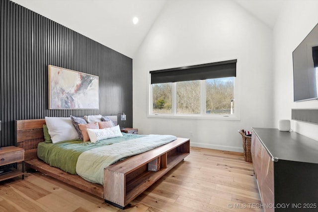 bedroom with light hardwood / wood-style flooring and high vaulted ceiling