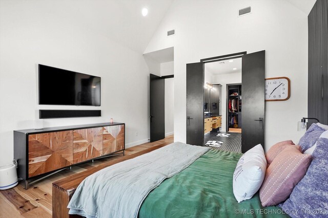 bedroom with high vaulted ceiling and light hardwood / wood-style flooring