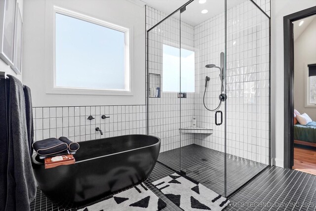 bathroom with tile patterned flooring, tile walls, and plus walk in shower