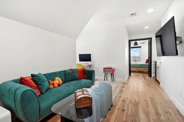 living room with light hardwood / wood-style floors and vaulted ceiling