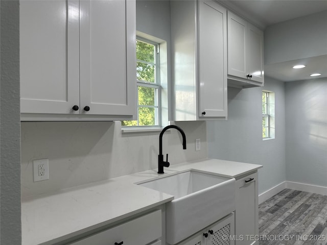 kitchen with white cabinets, sink, and light hardwood / wood-style flooring