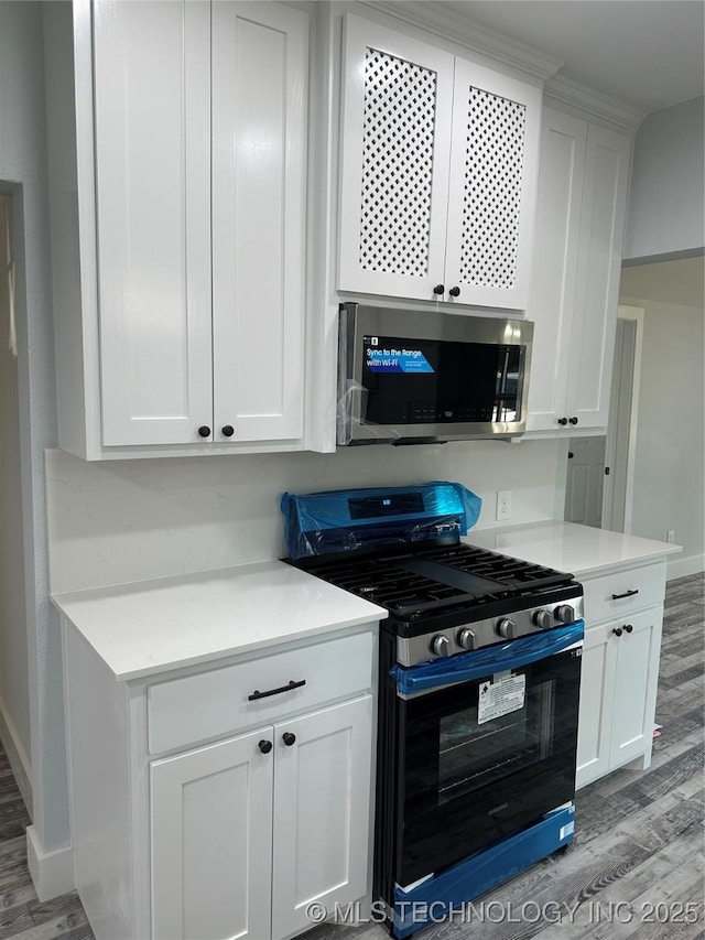 kitchen with hardwood / wood-style flooring, stainless steel appliances, and white cabinetry