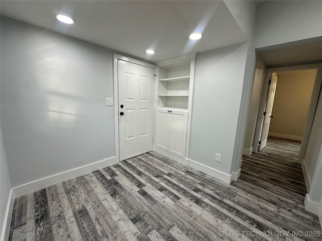 spare room featuring built in shelves and dark hardwood / wood-style flooring