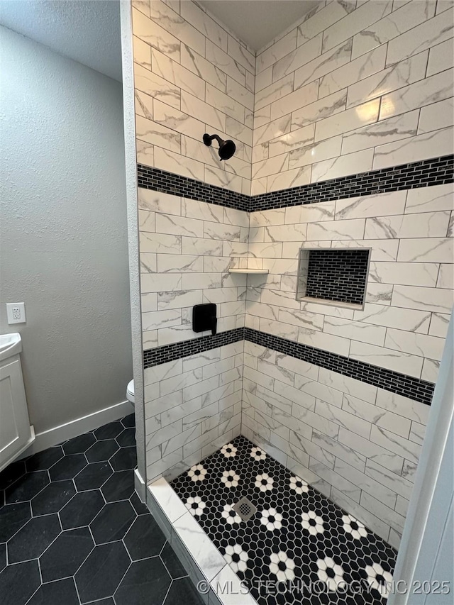 bathroom with toilet, a tile shower, and tile patterned floors