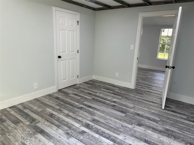 spare room with dark wood-type flooring and beamed ceiling