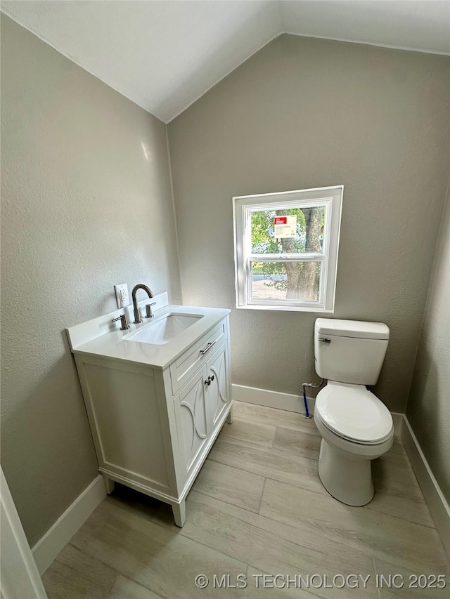 bathroom featuring vaulted ceiling, toilet, and vanity