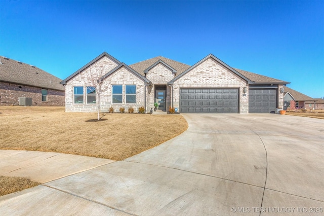 view of front of property featuring a front lawn, central air condition unit, and a garage