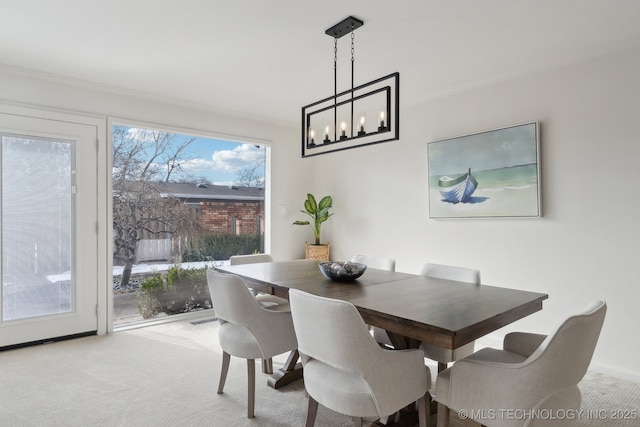 carpeted dining room with a notable chandelier, a wealth of natural light, and ornamental molding