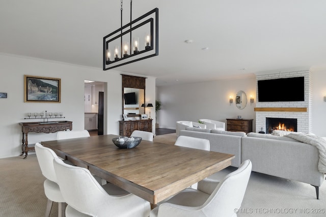 carpeted dining area with a brick fireplace and crown molding