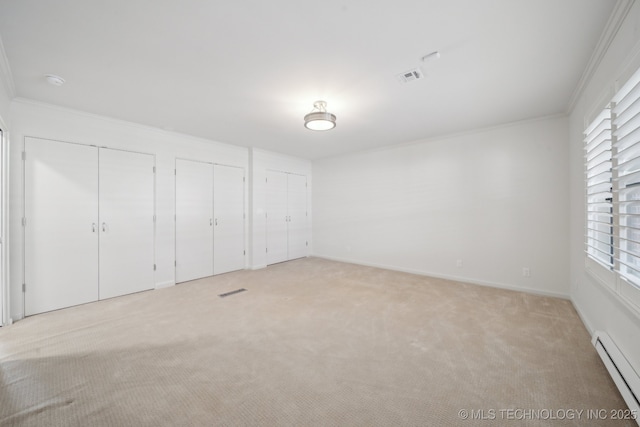 unfurnished bedroom with light colored carpet, a baseboard heating unit, crown molding, and two closets