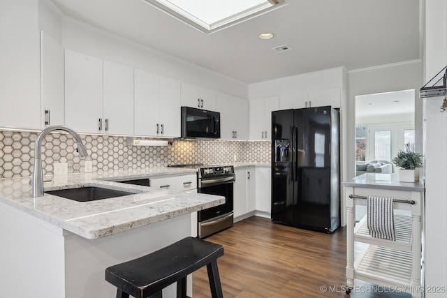 kitchen with light stone countertops, sink, white cabinetry, and black appliances