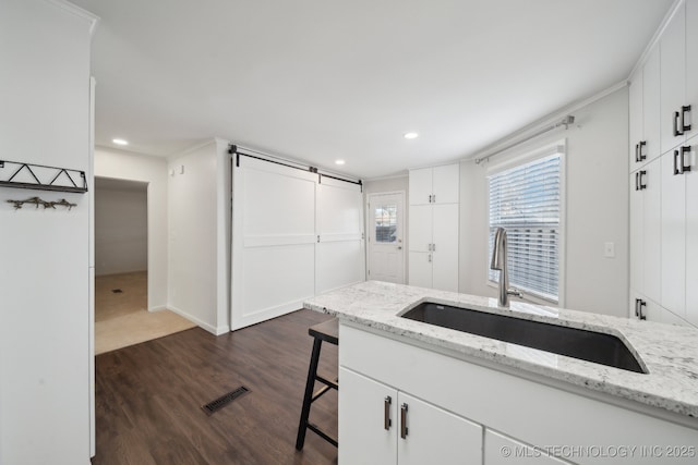 kitchen featuring a breakfast bar area, dark wood-type flooring, light stone countertops, white cabinets, and sink