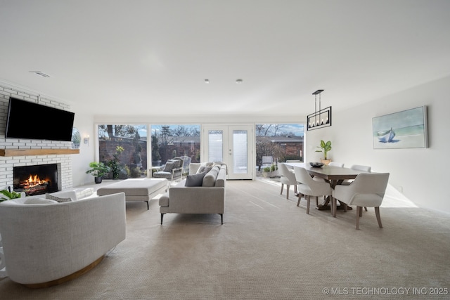 carpeted living room with french doors and a brick fireplace