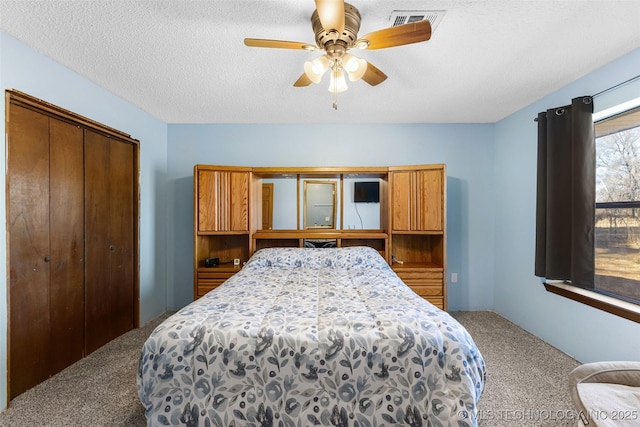 carpeted bedroom with a textured ceiling, ceiling fan, and a closet