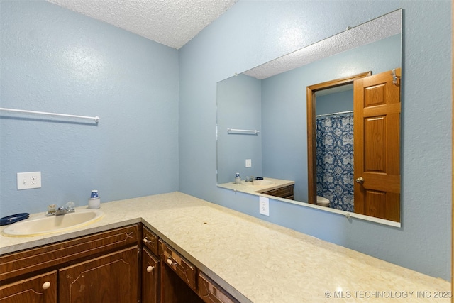 bathroom featuring vanity, toilet, and a textured ceiling