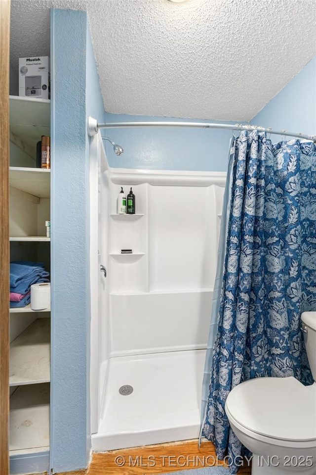 bathroom with curtained shower, toilet, and a textured ceiling