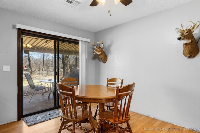 dining space featuring ceiling fan, a textured ceiling, and light wood-type flooring