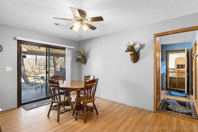 dining area with ceiling fan, light hardwood / wood-style flooring, and a textured ceiling