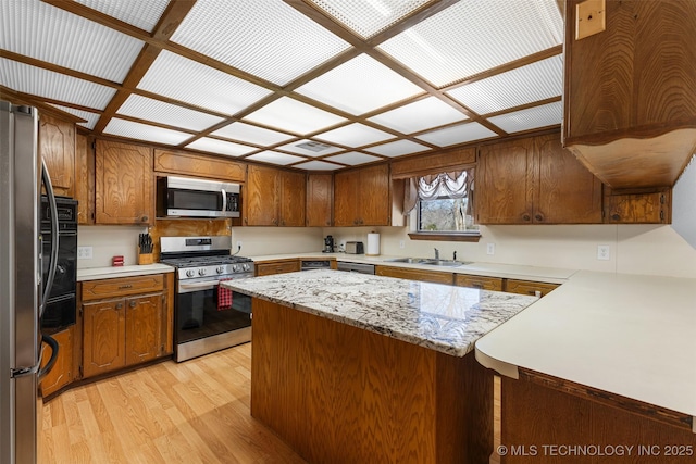 kitchen featuring stainless steel appliances, sink, kitchen peninsula, and light hardwood / wood-style floors