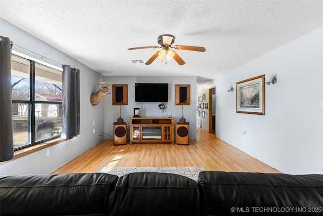 living room with ceiling fan, hardwood / wood-style flooring, and a textured ceiling