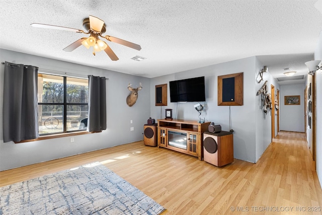 living room with ceiling fan, light hardwood / wood-style floors, and a textured ceiling