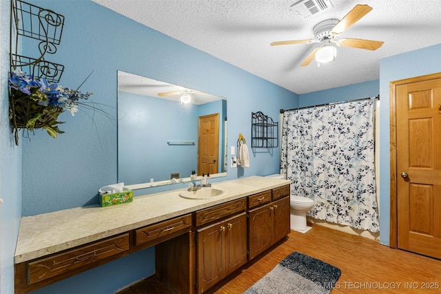 bathroom featuring hardwood / wood-style floors, vanity, ceiling fan, toilet, and a textured ceiling