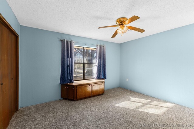 unfurnished bedroom featuring a closet, ceiling fan, carpet floors, and a textured ceiling