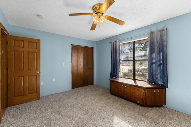 unfurnished bedroom featuring light carpet, a textured ceiling, ceiling fan, and a closet