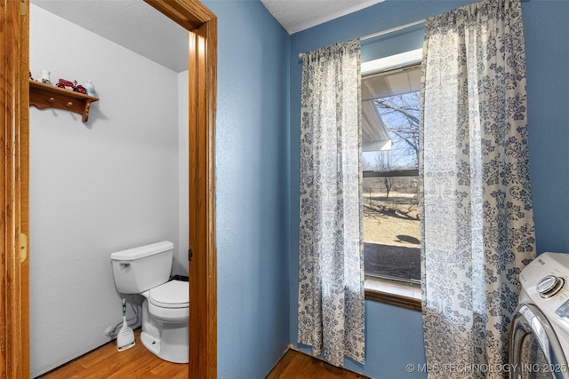 bathroom featuring washer / clothes dryer, hardwood / wood-style flooring, and toilet