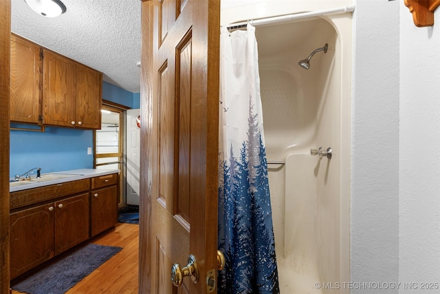 bathroom featuring vanity, curtained shower, hardwood / wood-style floors, and a textured ceiling