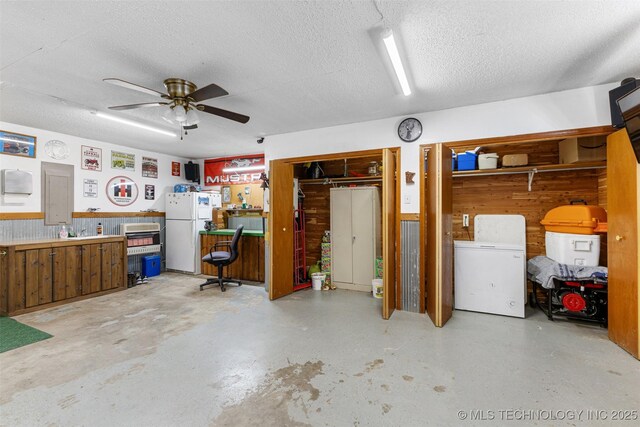 basement with ceiling fan, wooden walls, white fridge, and a textured ceiling