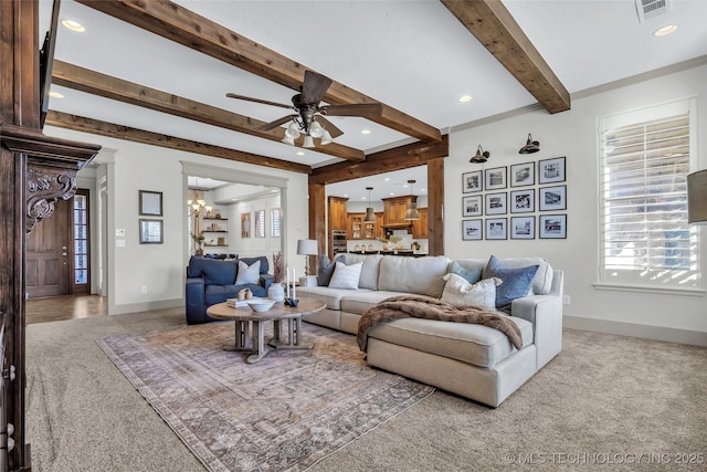 carpeted living room featuring ceiling fan with notable chandelier and beamed ceiling