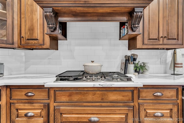 kitchen featuring stainless steel gas stovetop, tasteful backsplash, and light stone counters