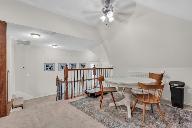 carpeted dining space with ceiling fan and lofted ceiling