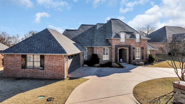 912 Dornick Dr, Ardmore, OK 73401 - french country style house with brick siding, concrete driveway, an attached garage, and roof with shingles
