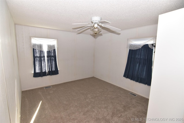 carpeted spare room featuring ceiling fan and a textured ceiling