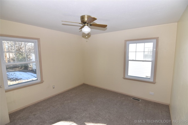 carpeted spare room featuring ceiling fan and a healthy amount of sunlight