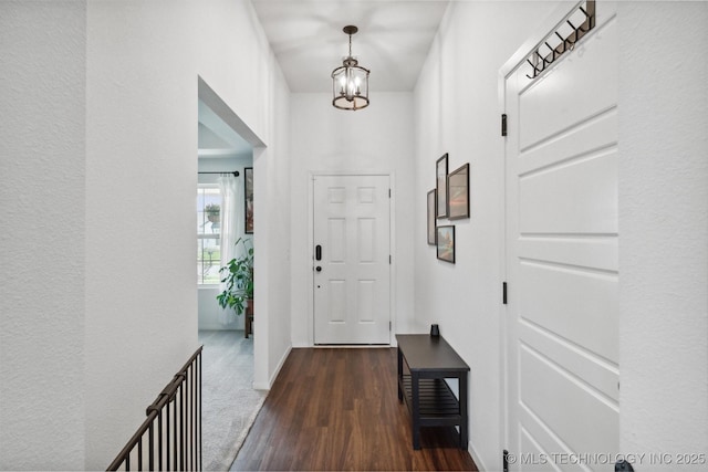 foyer featuring an inviting chandelier and dark wood-type flooring