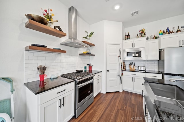 kitchen with appliances with stainless steel finishes, exhaust hood, white cabinets, decorative backsplash, and dark hardwood / wood-style flooring