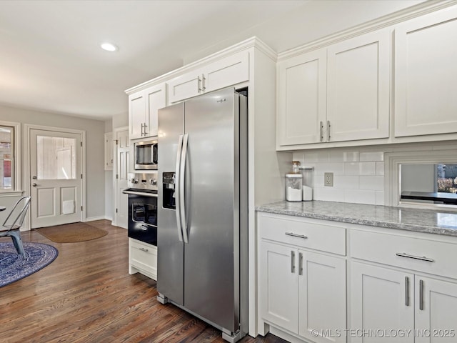 kitchen with white cabinetry, appliances with stainless steel finishes, decorative backsplash, dark wood-type flooring, and light stone counters