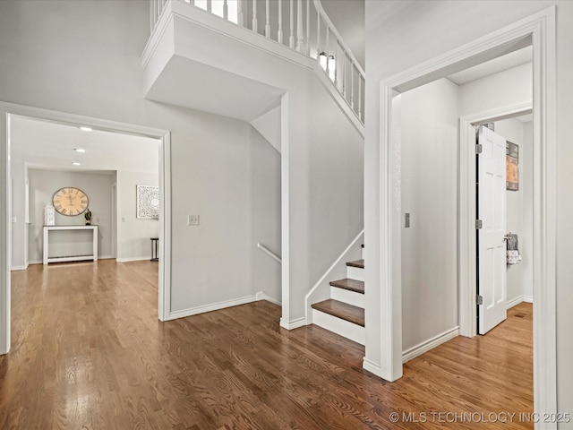 stairs featuring a high ceiling and hardwood / wood-style flooring