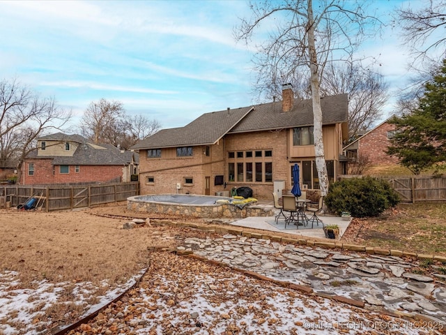 snow covered back of property featuring a patio