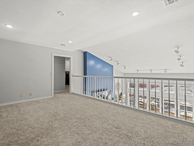 carpeted spare room with a textured ceiling and lofted ceiling