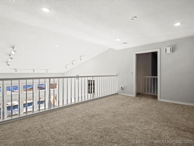 carpeted spare room with a textured ceiling and lofted ceiling