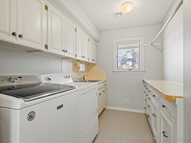 clothes washing area featuring sink, separate washer and dryer, and cabinets