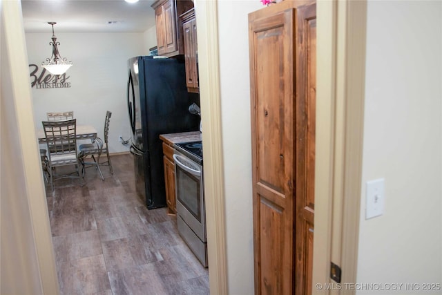 kitchen with hanging light fixtures, stainless steel electric range, dark wood-type flooring, and black fridge