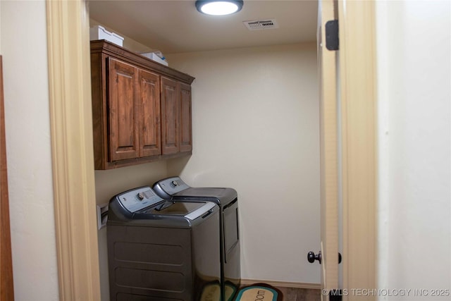 laundry room featuring washer and dryer and cabinets