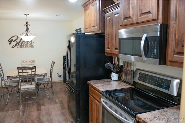 kitchen with dark wood-type flooring, stainless steel appliances, and pendant lighting