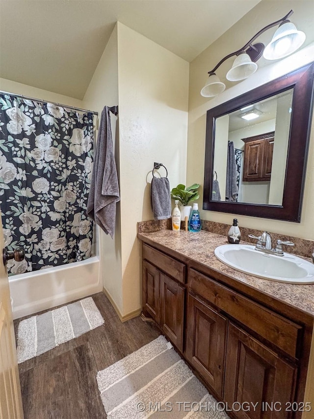 bathroom featuring wood-type flooring, vanity, and shower / bathtub combination with curtain